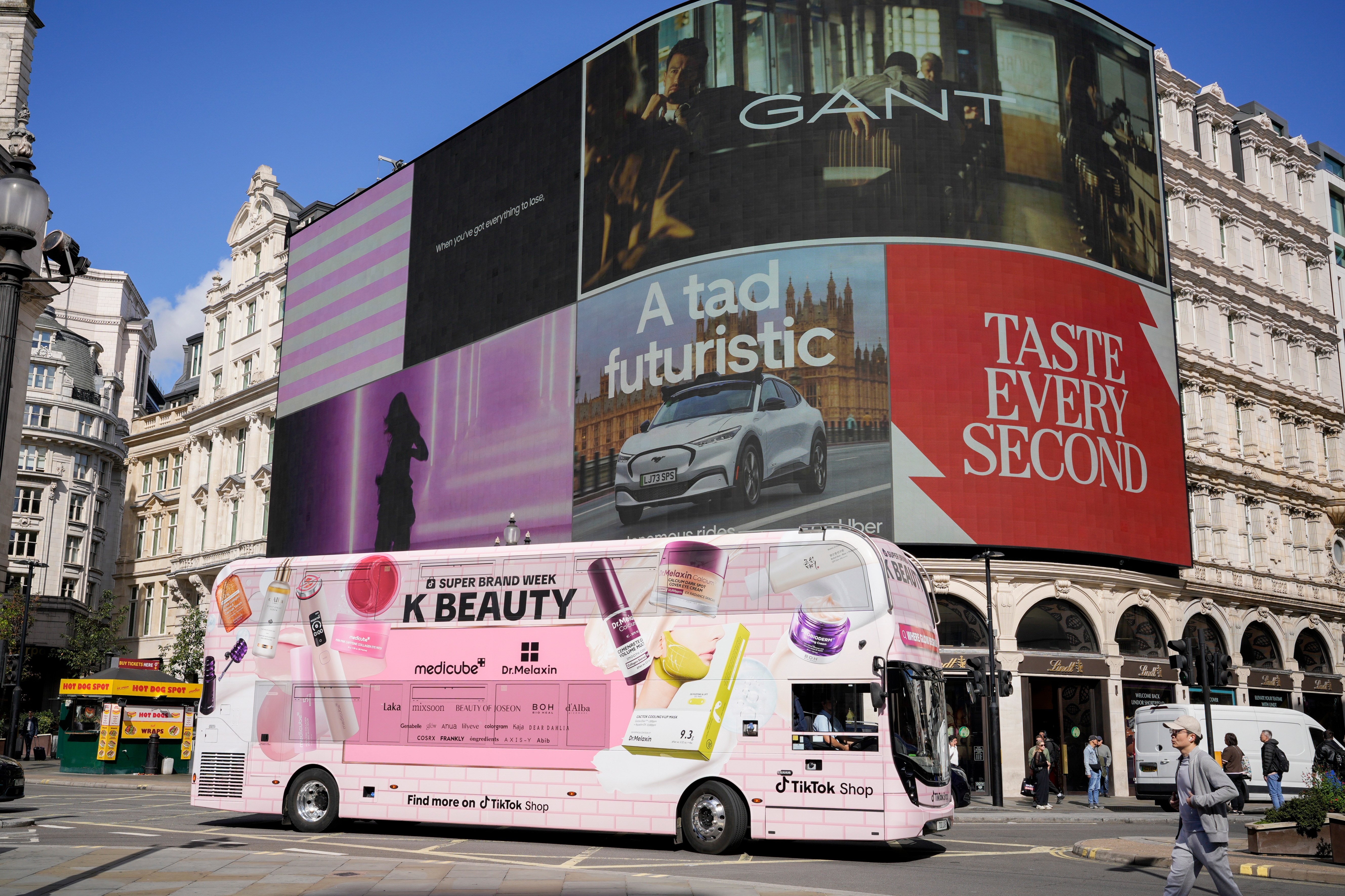 Pink TikTok Shop K-BEAUTY bus in Piccadilly Circus beneath the curved digital screens