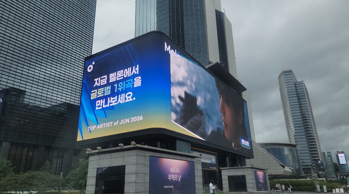 Melon "Top Artist of Jun 2026" campaign on the curved COEX K-POP LIVE screen on an overcast day, Seoul