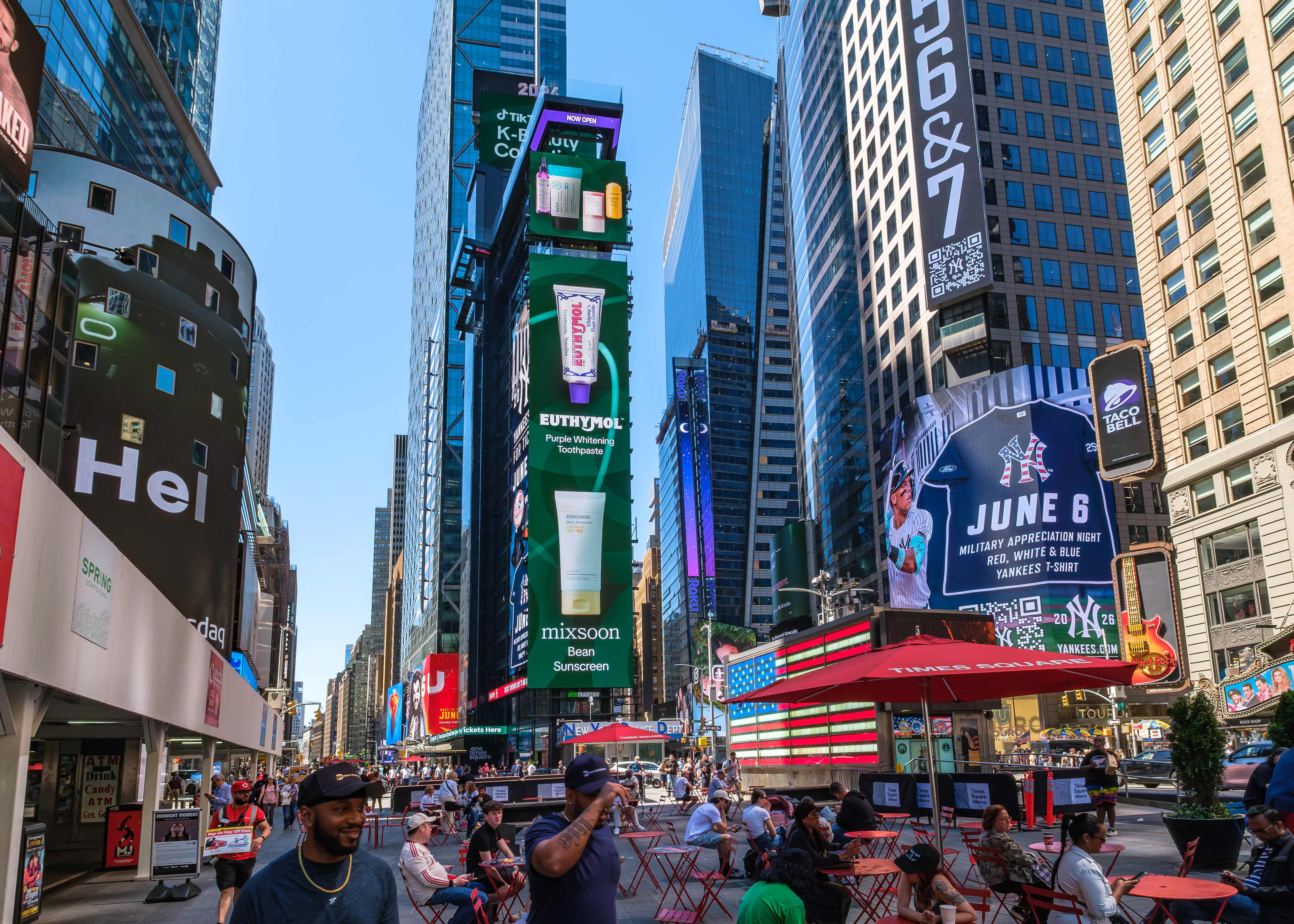 Euthymol Purple Whitening Toothpaste and mixsoon Bean Sunscreen creatives on the vertical Times Square screens